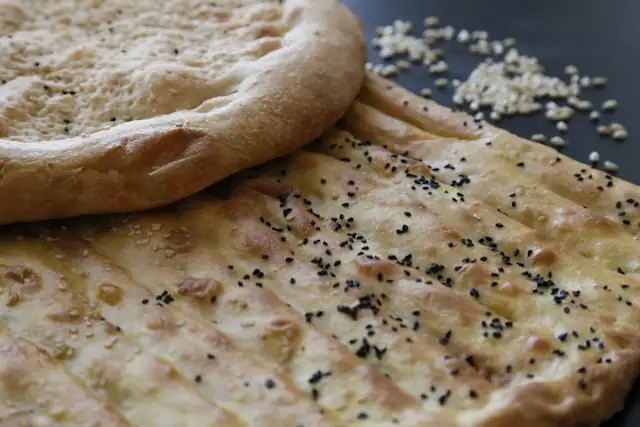 Naan à l'ail et coriandre avec des graines, un pain indien savoureux et aromatique, parfait pour une collation saine et nourrissante.